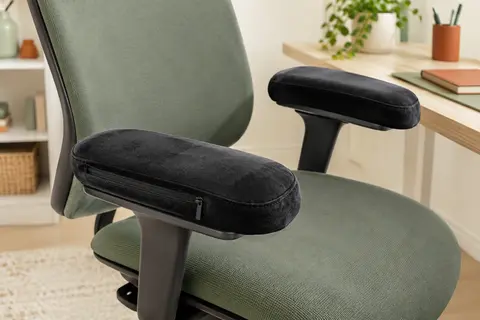 Deux coussinets noirs en mousse à mémoire de forme installés sur les accoudoirs d’une chaise de bureau.