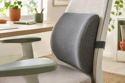 Coussin lombaire gris en maille posé sur le dossier d’une chaise de bureau dans un espace lumineux
