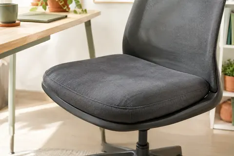 Coussin d’assise rembourré en tissu gris foncé posé sur une chaise de bureau dans un espace lumineux