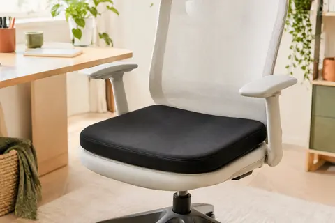 Coussin d’assise noir en mousse à mémoire posé sur une chaise de bureau claire.
